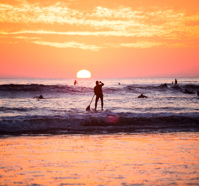 Sunset surfers and paddleboarders in Carlsbad, California