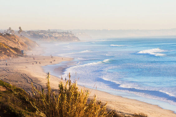 The Carlsbad coast in the daytime, with waves crashing onto sandy beaches