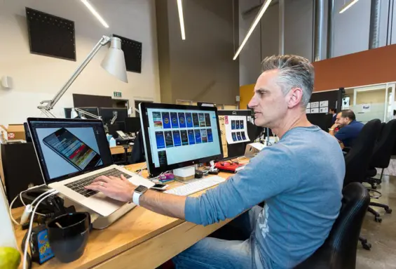 Working between two screens, a man creatively builds web tools