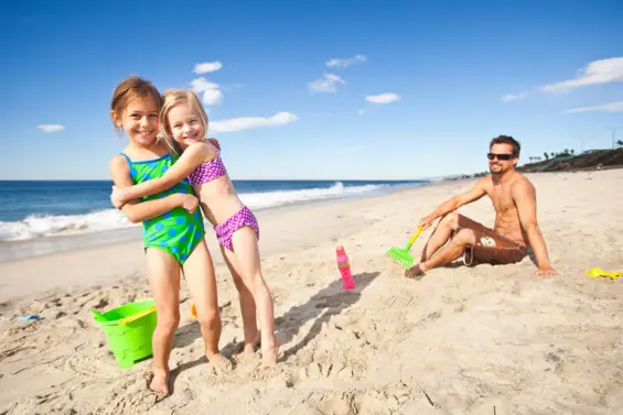 Two young girls hug each other on the beach