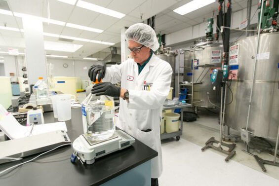 A lab worker fills a large container with liquid