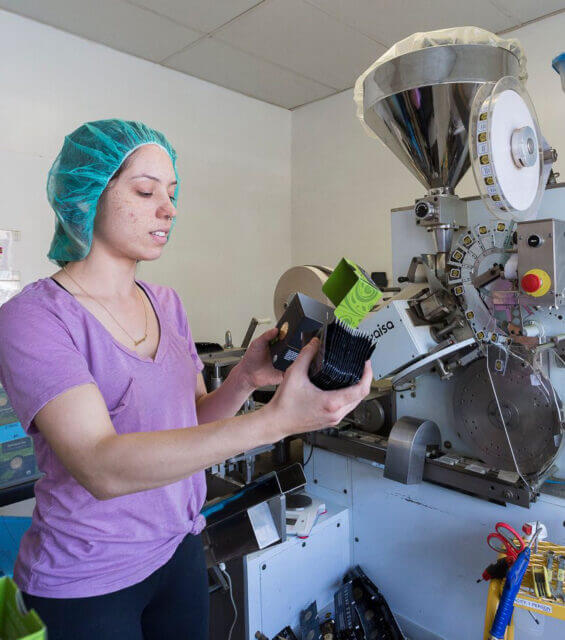 A woman at the Buddha Teas manufacturing facility works on machinery